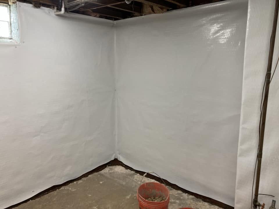 Basement corner fully lined with white waterproofing wall membrane