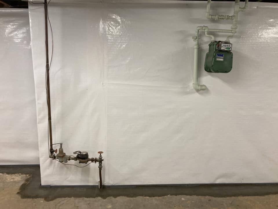 Waterproofed basement wall with exposed water main and gas meter